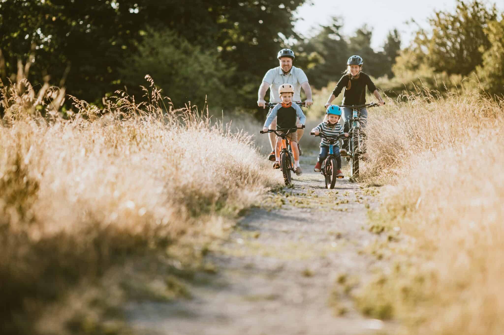 a family of 4 riding towards you on a path through tall grass