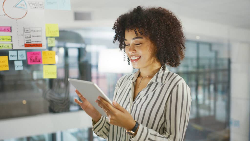 A woman in an office holding a tablet as if she is collaborating with her team