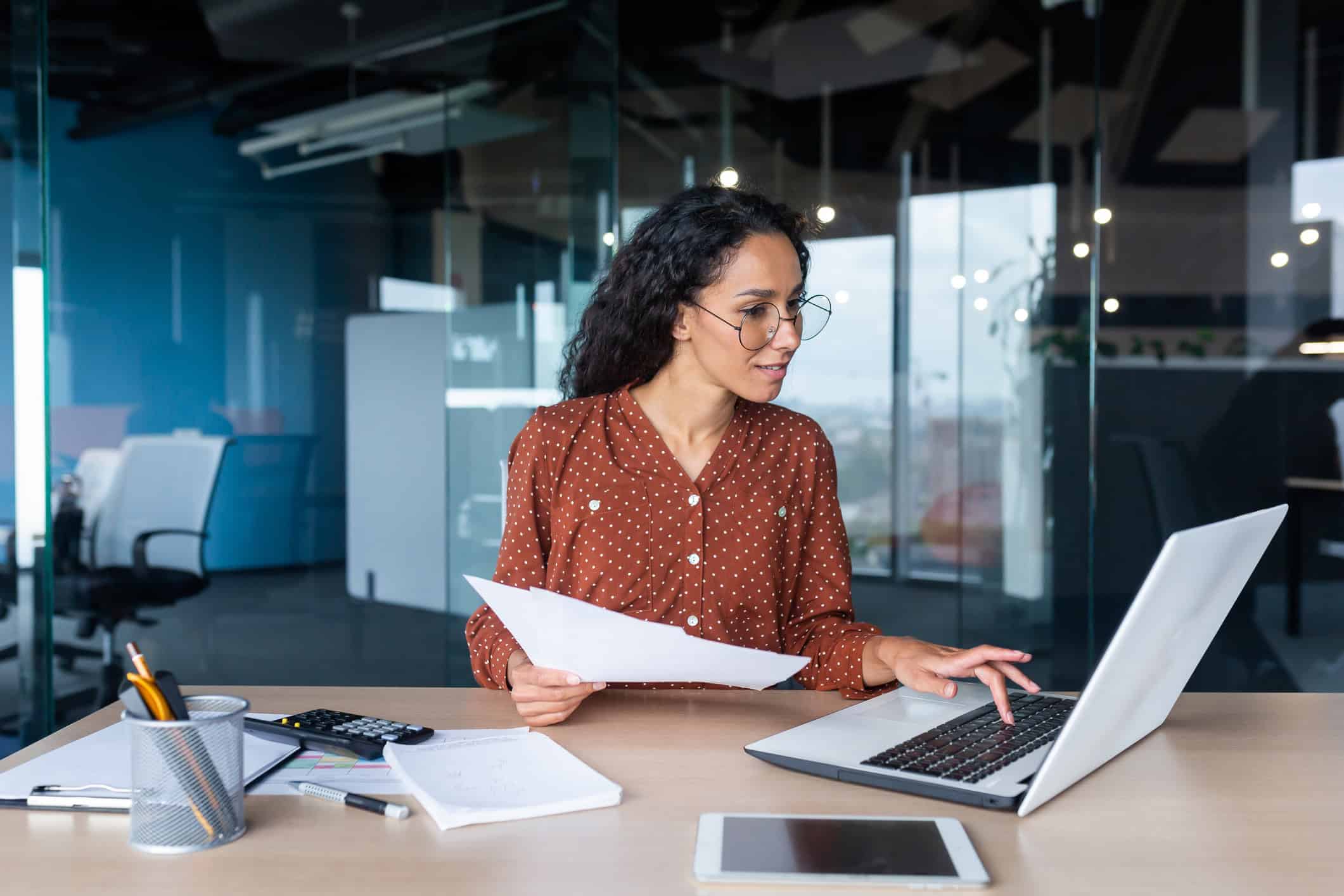 Female Project Manager sitting at a desk working on a laptop 